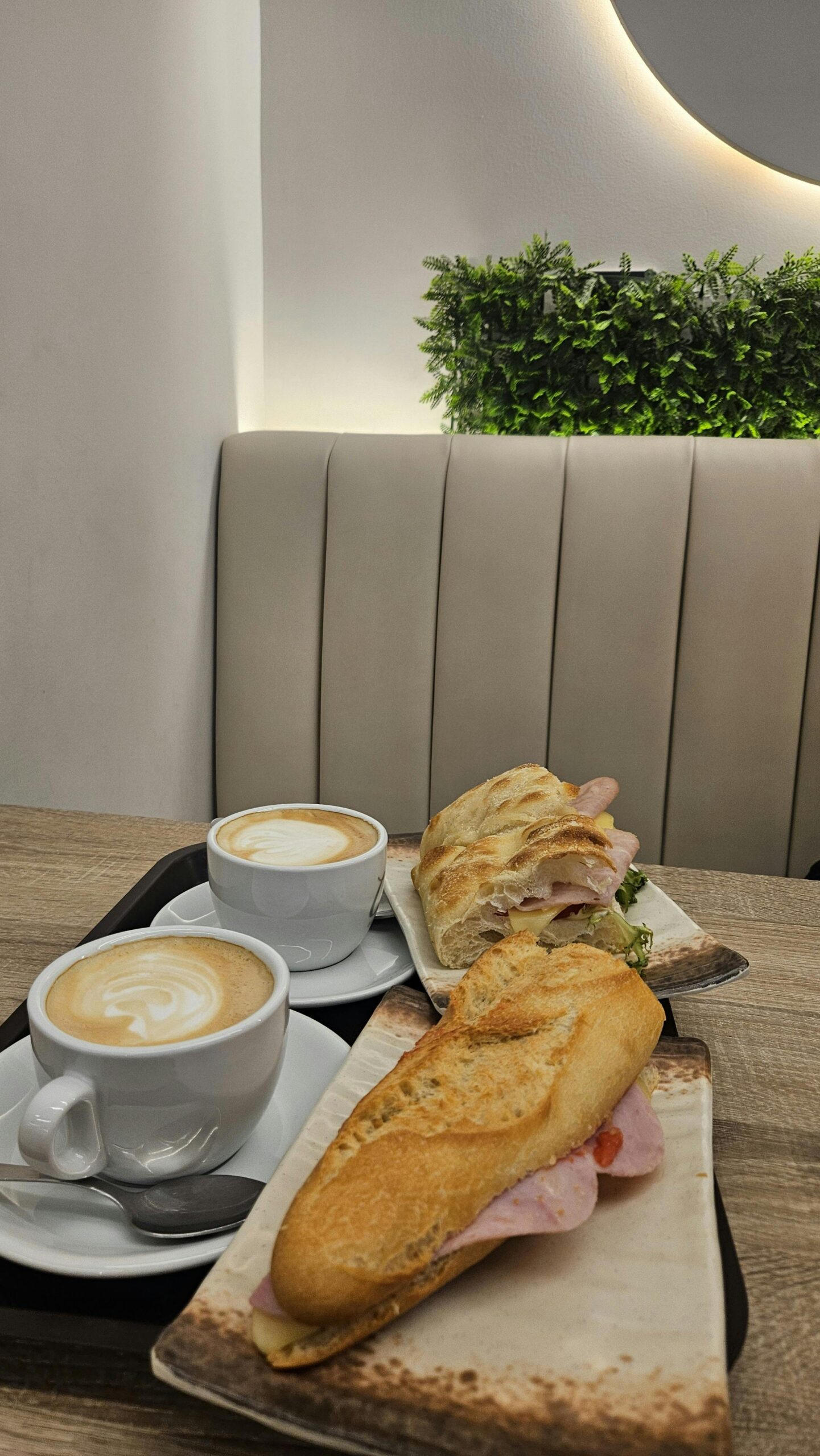 A cozy café breakfast setting in Barcelona featuring lattes and fresh sandwiches.